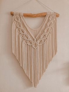 a macrame wall hanging on a white wall