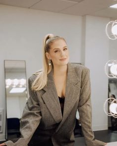 a woman sitting at a desk in front of a mirror with her hands on her hips