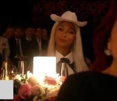 a woman wearing a cowboy hat sitting at a table with candles in front of her