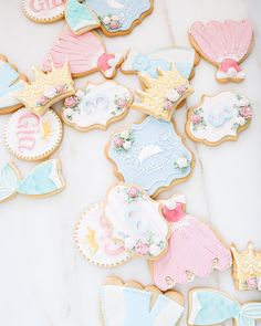 some decorated cookies sitting on top of a white table with pink and blue frosting