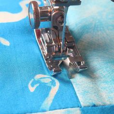 the sewing machine is on top of the blue fabric with white and gray designs around it