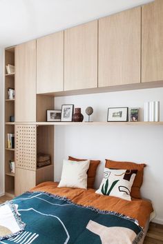 a bed sitting in a bedroom next to a wooden shelf filled with pictures and books