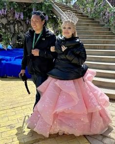 two people standing next to each other in front of some stairs