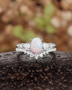 an opal and diamond ring on top of a rock