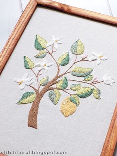 an embroidered tree with white flowers and green leaves