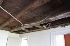 an electrical cord is attached to the ceiling in a room with white walls and wooden beams