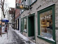 an alley way with shops and stores on the side walk in winter, along with snow covered sidewalks