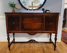 a wooden dresser with a mirror above it and a rug on the floor next to it