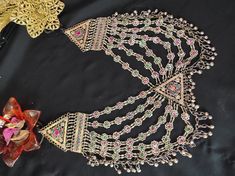 * This heavily embellished, seven-layer necklace is an epitome of tradition. Each string of the piece has multicolour stones embedded within the tiny floral motifs, complimenting the tribal style of the ornament. This astonishing piece is handcrafted by the local artisans of south Asia, who have kept such style of ornaments alive in the fashion. You can Pair this astonishing piece with any traditional attire to complement your look or add a pinch of ethnic touch to your trendy outfit. Note: The Traditional Jeweled Necklaces For Festivals, Multicolor Jewelry For Festival Celebration, Multicolor Festival Jewelry For Celebration, Multicolor Jewelry For Celebration Festival, Multicolor Jeweled Bridal Necklace For Festive Occasions, Handmade Multicolor Bridal Necklace For Festivals, Bohemian Jeweled Necklace For Celebration, Traditional Multi-strand Silver Necklace, Traditional Handmade Multicolor Bridal Necklace