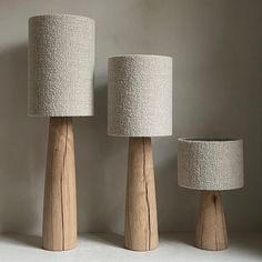 three wooden lamps sitting next to each other on a white shelf in front of a wall