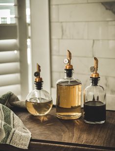 two glass bottles sitting on top of a wooden table next to a towel and bottle opener