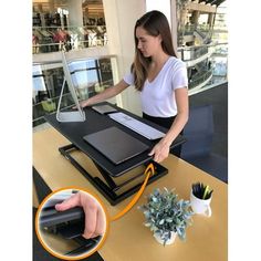 a woman standing at a desk with a laptop on it