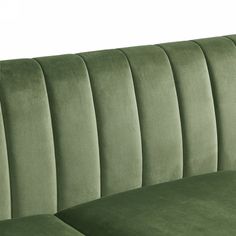 the back of a green velvet couch with pleated upholstered arms and legs