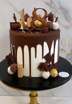 a chocolate cake with white and gold decorations