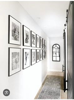 a hallway with pictures hanging on the wall and a rug in front of an open door