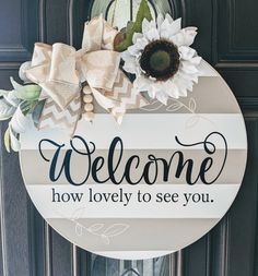 a welcome sign hanging on the front door with sunflowers and ribbon around it