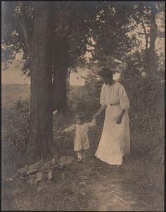 an old black and white photo of a woman holding the hand of a child