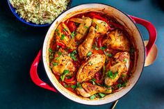 a pot filled with chicken and rice next to a bowl full of other food on a table