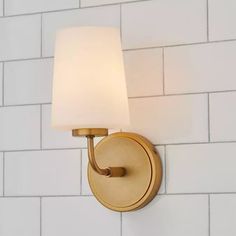 a wall light that is on the side of a white brick wall with a square shade