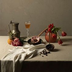 a table topped with flowers and other items next to a vase filled with water on top of a table