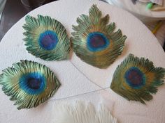 three peacock feathers on top of a white table