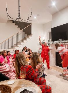 a group of women in pajamas sitting around a living room with christmas decorations on the walls