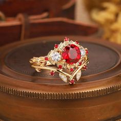 a red ring sitting on top of a wooden table next to some other jewelry items