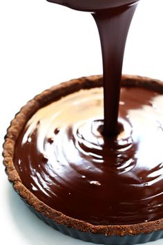 a chocolate tart pie being drizzled with melted chocolate