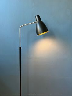 a black lamp on a wooden floor next to a blue wall