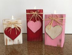 three small wooden blocks with hearts tied to them, one is pink and the other is red