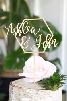 a wedding cake topper with the word's initials on it and a pink flower