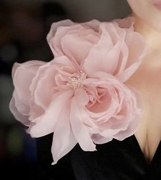 a woman wearing a pink flower on her chest and black dress with large flowers in the back