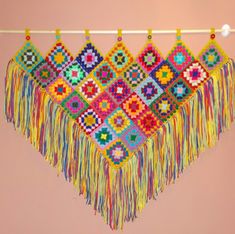 a multicolored crocheted wall hanging with beads and tassels on it