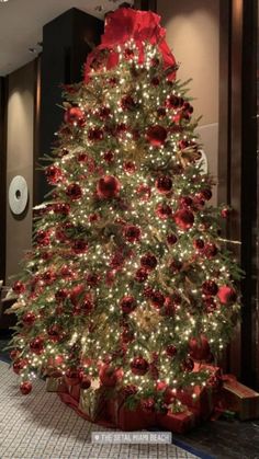 a decorated christmas tree with red and gold ornaments on it's branches in a lobby