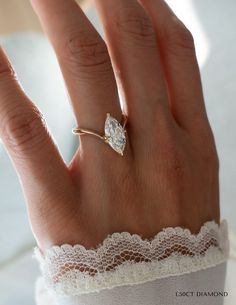 a woman's hand wearing a gold ring with a pear shaped diamond on it