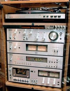 an old stereo system is stacked on top of each other in front of a wooden shelf