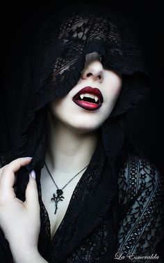 a woman with red lipstick and black lace on her face, wearing a veil over her head