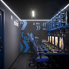 a gaming room with blue chairs and black walls, along with video game screens on the wall