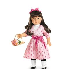 a doll holding a basket with flowers and a pink bow on it's head