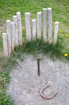 an old rusty horseshoe sits in the middle of a gravel area next to a wooden fence