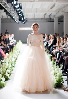 a woman in a white dress walking down a runway