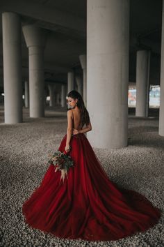 a woman in a long red dress is standing on the ground with her back to the camera