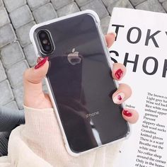 a woman holding up her iphone case in front of an open book with the words tokyo shop on it