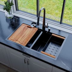 a kitchen sink with two wooden cutting boards on the bottom and an open window behind it