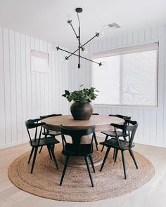 a dining room table with chairs and a vase on the rug in front of it