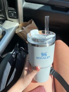 a woman holding a cup in her hand while sitting in the back seat of a car