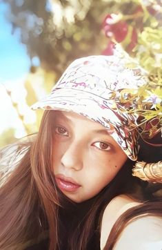 a young woman wearing a hat and posing for a photo in front of some trees