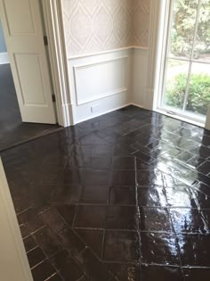 an empty room with tile flooring and white trim on the walls, windows, and door