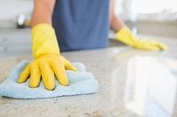 a person with yellow gloves on their hands is cleaning the counter top in front of them