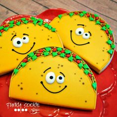 three decorated cookies on a red plate with green and red trimmings, each shaped like a taco